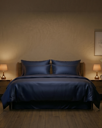 Midnight navy blue bedding set on a bed in a dimly lit bedroom with two lamps and a painting.
