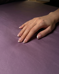 Hand with manicured nails on a deep plum sateen  fabric surface