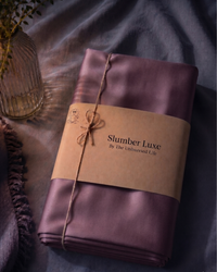 Deep plum sateen fabric with 'Slumber Luxe' label on a dark surface