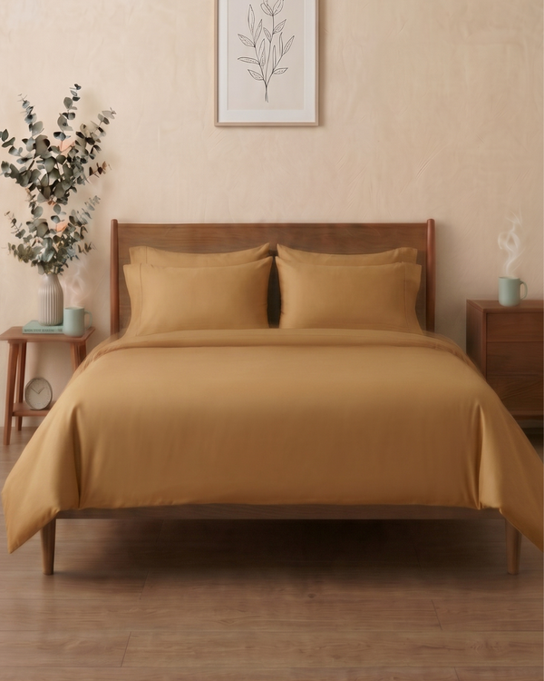Bed with Golden sand colour bedding in a room with wooden furniture and decor.