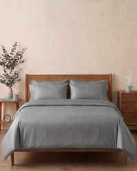 Silver Grey bedding set on a wooden bed with matching headboard and nightstands in a bedroom setting.